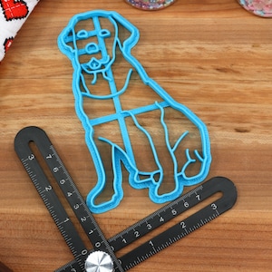 Peut inclure: Un emporte-pi&egrave;ce en plastique bleu en forme de chien assis. L'emporte-pi&egrave;ce est sur une surface en bois avec une r&egrave;gle.