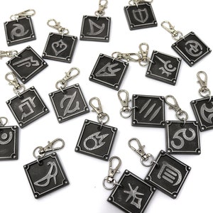 May include: A set of 18 silver-colored metal keychains with different symbols on each. The keychains are square-shaped and have a silver-colored metal ring.