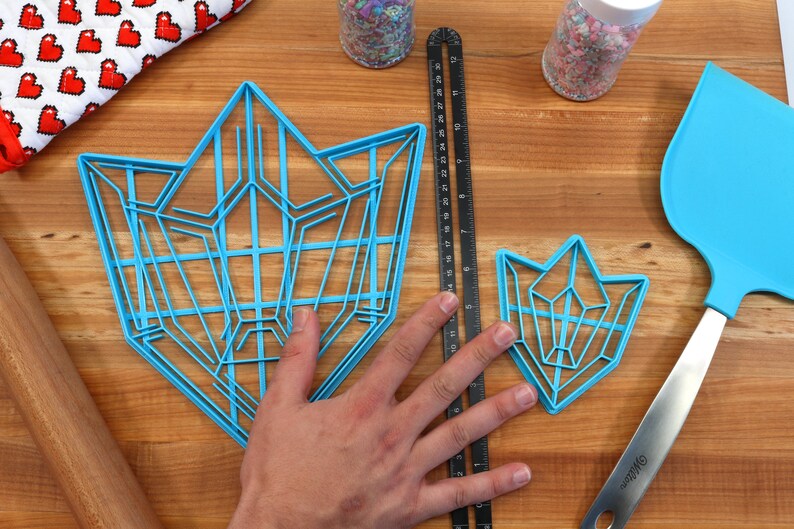 Puede incluir: Dos cortadores de galletas de pl&aacute;stico azul con forma de cristales geom&eacute;tricos. El cortador m&aacute;s grande mide aproximadamente 15 cm de ancho y el m&aacute;s peque&ntilde;o aproximadamente 7,5 cm de ancho.