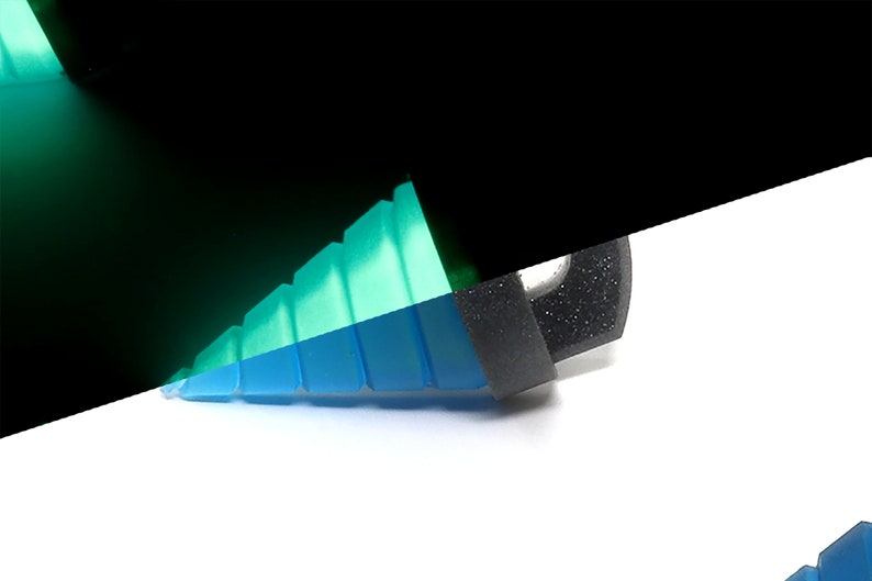 May include: A close-up of a multi-colored, geometric object. The object is primarily blue and green, with a black section on the right. The object appears to be made of a translucent material, with a stepped design.