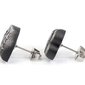 May include: A pair of black stud earrings with a silver post and butterfly design.