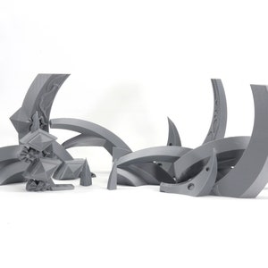 May include: A set of 3D printed gray plastic pieces that form a geometric design. The pieces are curved and have intricate details.