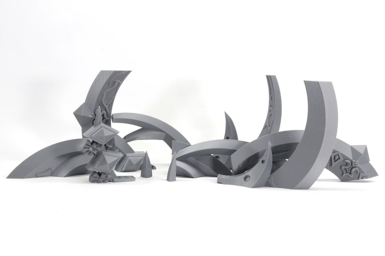 May include: A set of 3D printed gray plastic pieces that form a geometric design. The pieces are curved and have intricate details.