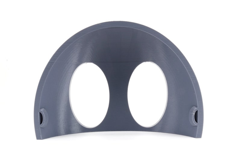 May include: A gray plastic half-dome with two circular openings. The dome is designed to be used as a wall mount for two round objects.