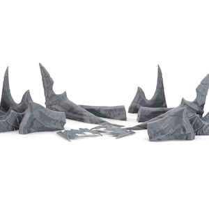 May include: A set of eight grey plastic model pieces, resembling jagged, sharp, and pointy rock formations. These pieces are likely for use in a tabletop game or miniature wargaming.