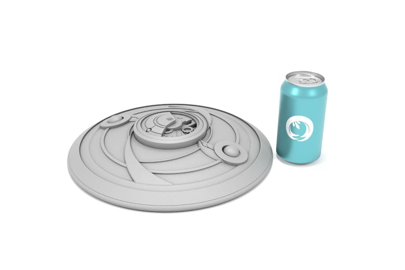 May include: A light gray, circular, decorative object with a detailed central design and a series of concentric rings. Next to it is a light blue can with a white logo. The objects are on a white background.
