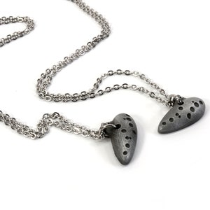 May include: Two silver chains with heart-shaped pendants. The pendants are textured and have a gray finish.