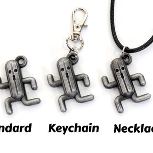 May include: Three silver-colored metal charms in the shape of a running cactus monster. The charms are shown in three different styles: standard, keychain, and necklace.