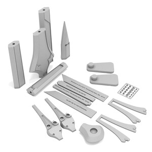 May include: A collection of light gray 3D-printed components, including rectangular bars, angled pieces, and various geometric shapes. Some pieces have text. The objects are arranged on a white background.