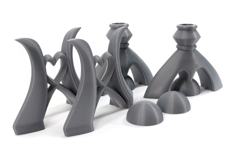 May include: Set of five gray 3D printed candle holders. The candle holders are shaped like hearts and have a modern design.