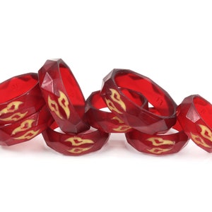 May include: A group of red silicone rings with a gold flame design. The rings are stacked on top of each other.