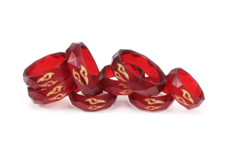 May include: A group of red silicone rings with a gold flame design. The rings are stacked on top of each other.