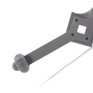 May include: A gray plastic sword with a rounded handle and a detailed hilt. The hilt has a square opening and several small holes.