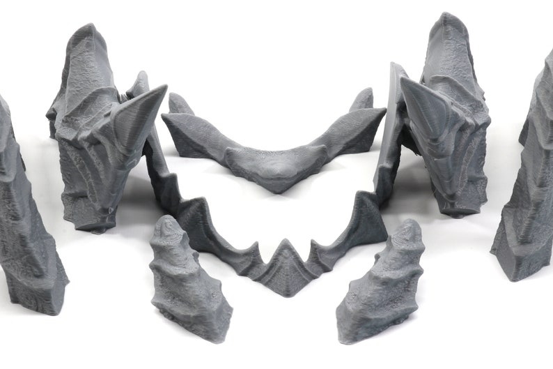 May include: A set of six grey 3D printed pieces that can be assembled to create a dragon head sculpture.