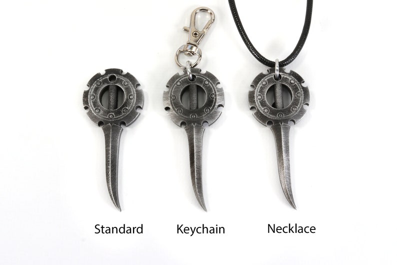 May include: Three silver-toned metal pendants with a circular design and a pointed blade. The pendants are shown in three different styles: standard, keychain, and necklace.