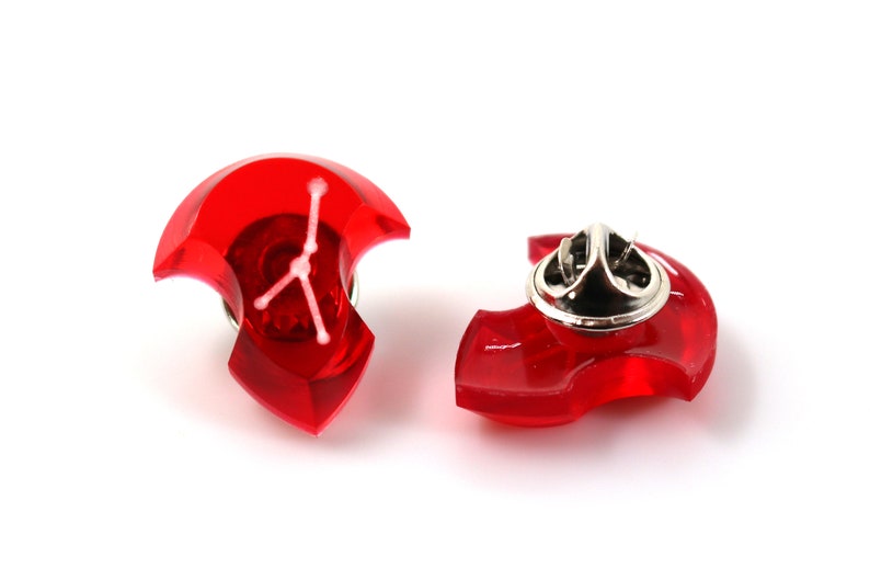 May include: Two red plastic pinback buttons with a white star design. The buttons are shaped like a crescent moon.