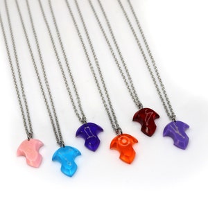 Puede incluir: Siete collares de plata con colgantes de diferentes colores. Los colgantes tienen forma de p&aacute;jaro con un dise&ntilde;o de constelaci&oacute;n. Los colores de los colgantes son rosa, azul, morado, rojo, naranja y dos tonos de morado.