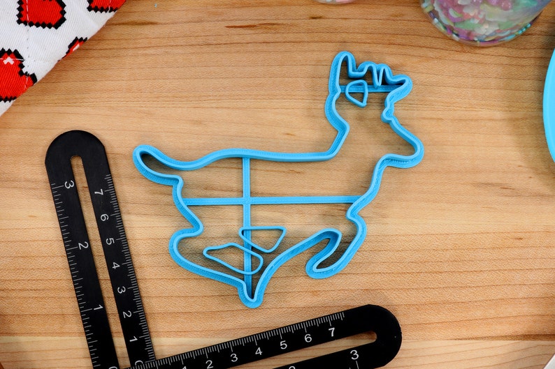 Op de afbeelding: Een lichtblauwe plastic koekjesvormer in de vorm van een rendier. De vormer is ongeveer 10 cm hoog en 12,5 cm breed.