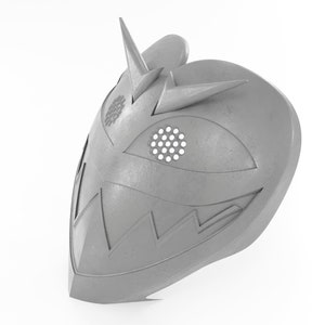 May include: A gray, metallic mask with a sharp, pointed design. The mask has a large, open eye hole with a circular pattern and a jagged, toothy mouth.