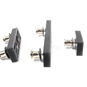 May include: Three gray plastic snap fasteners with silver metal posts. The fasteners are in different sizes and shapes.