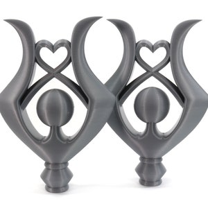 May include: Two gray, abstract sculptures with a heart and circle design. The sculptures are made of a smooth, matte material and have a modern, minimalist aesthetic.