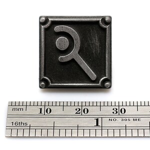 Peut inclure: Une &eacute;pingle en m&eacute;tal argent&eacute; avec un fond noir et un symbole stylis&eacute; d'un croissant de lune et d'un cercle. L'&eacute;pingle mesure environ 2,5 cm de large.