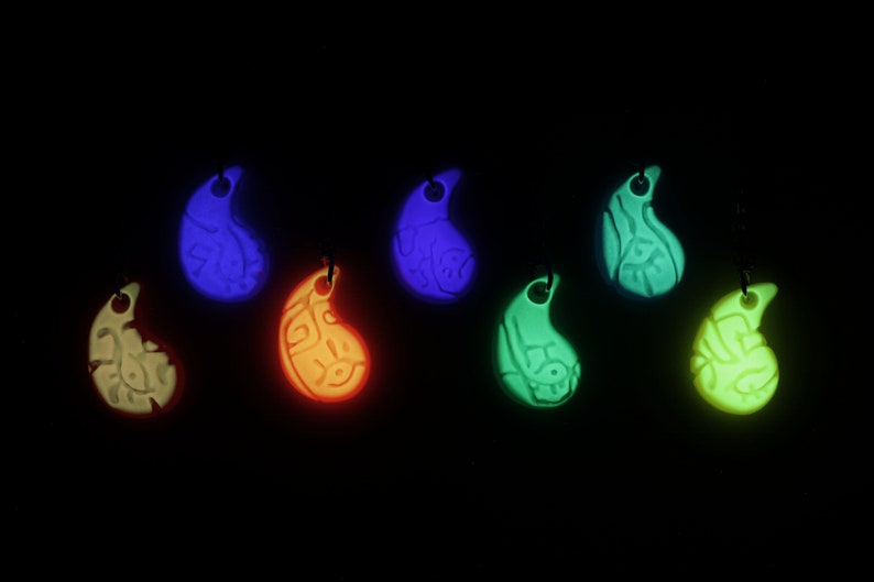May include: Seven glow-in-the-dark pendants in different colours, including white, blue, green, orange, and yellow. Each pendant is shaped like a teardrop and has a detailed design.