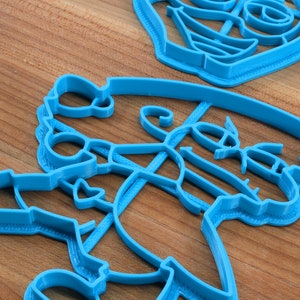 Puede incluir: Un juego de cuatro cortadores de galletas de pl&aacute;stico azul con forma de mu&ntilde;eco de nieve, reno, calcet&iacute;n y &aacute;rbol de Navidad.
