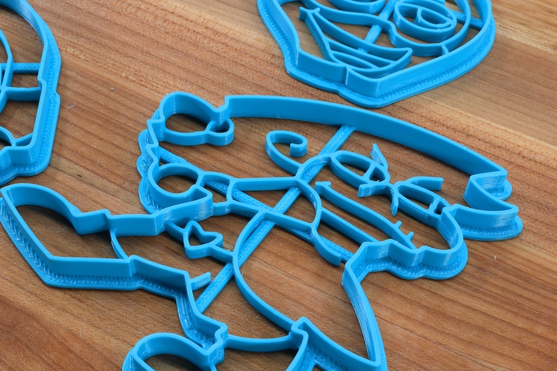Puede incluir: Un juego de cuatro cortadores de galletas de pl&aacute;stico azul con forma de mu&ntilde;eco de nieve, reno, calcet&iacute;n y &aacute;rbol de Navidad.