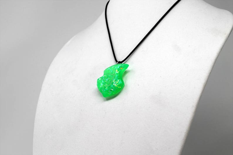 Op de afbeelding: Een ketting met een groene opaal hanger aan een zwart koord. De opaal heeft een vrije vorm, is lichtgroen en heeft een iriserende glans.