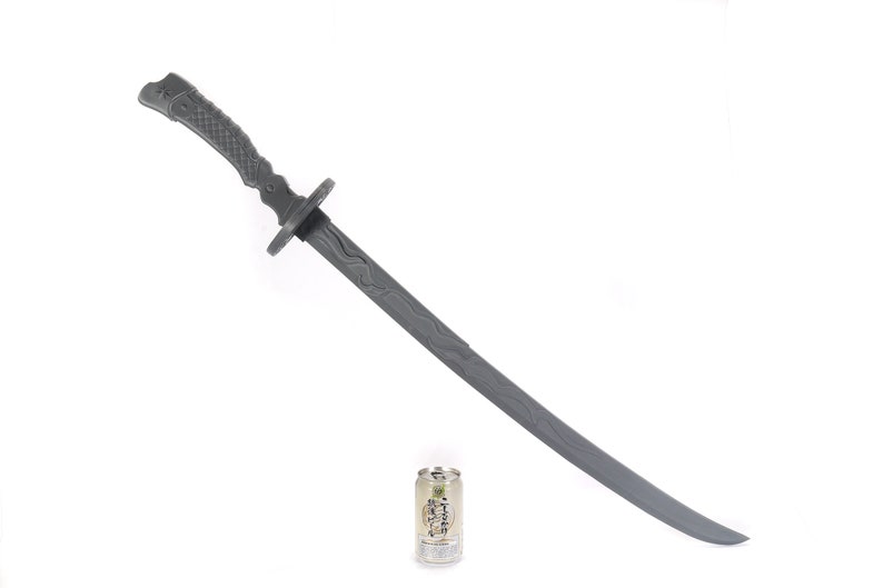 Może przedstawiać: Szary plastikowy miecz katana z teksturowaną rękojeścią i ostrzem. Miecz jest wyświetlany na białym tle. Mała puszka z japońskim tekstem znajduje się u podstawy miecza.