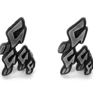May include: A pair of silver-colored earrings shaped like a stylized letter "G".