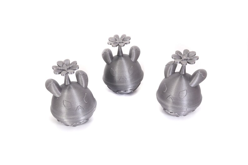 May include: Three small, gray, 3D printed figurines of a cartoon character with bunny ears and a flower on top.