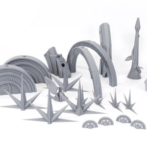 May include: A collection of gray 3D-printed architectural models, including arched structures, spires, and circular elements. The pieces are arranged on a white surface, showcasing intricate details and geometric designs. Ideal for hobbyists and model builders.