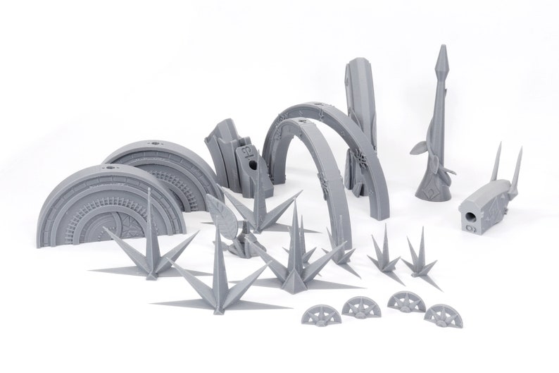 May include: A collection of gray 3D-printed architectural models, including arched structures, spires, and circular elements. The pieces are arranged on a white surface, showcasing intricate details and geometric designs. Ideal for hobbyists and model builders.