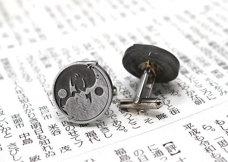 May include: A pair of silver cufflinks with a yin yang design. One cufflink features a black yin and a silver yang, while the other cufflink features a silver yin and a black yang.