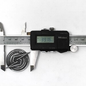 May include: A silver metal pin with a stylized lightning bolt design is measured with a digital caliper. The caliper reads 39.16 mm.