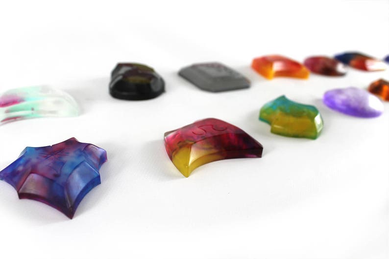 May include: Assortment of colorful, translucent, and opaque resin pieces in various shapes, including a star, crescent moon, and rectangular shapes. Some pieces have a swirl pattern, while others have a solid color.