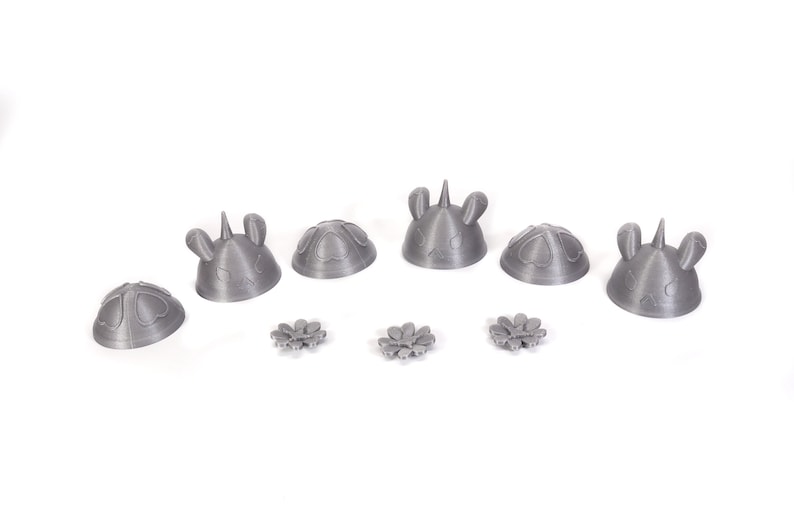 May include: A set of six gray 3D printed unicorn head figurines with a flower design. The figurines are arranged in a row on a white surface.