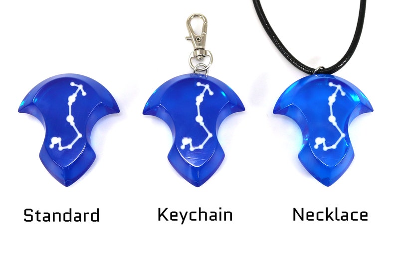 May include: Three versions of a blue pendant with a white constellation design. The pendant is available as a standard piece, a keychain, and a necklace.