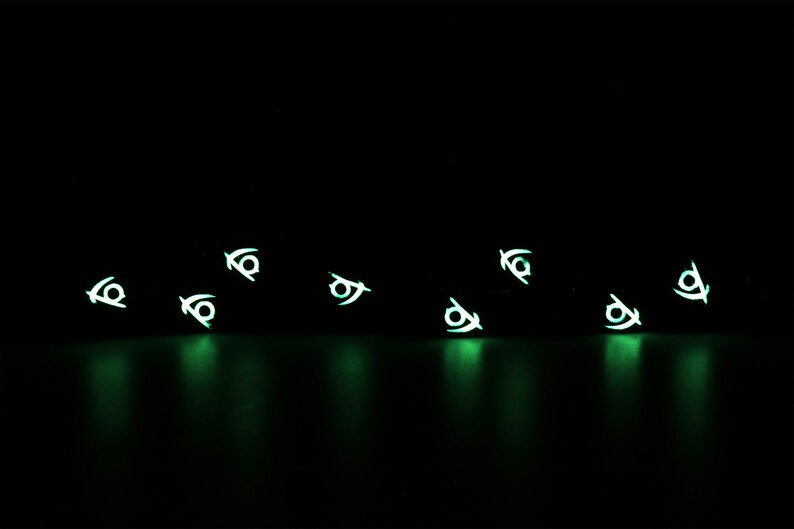May include: A black background with multiple glowing green symbols scattered across the surface. The symbols are all the same and resemble a stylized eye.