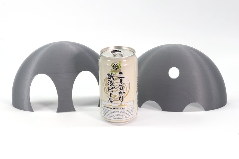 May include: Two gray 3D printed half-dome shapes with holes, one with two holes and the other with one hole, surrounding a can of Japanese beer labeled "Ichi-go Ichi-e" with Japanese text.