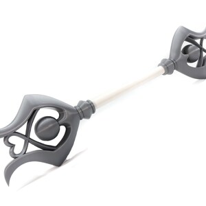 May include: A gray 3D printed wand with two heart-shaped designs on each end. The wand has a white shaft.