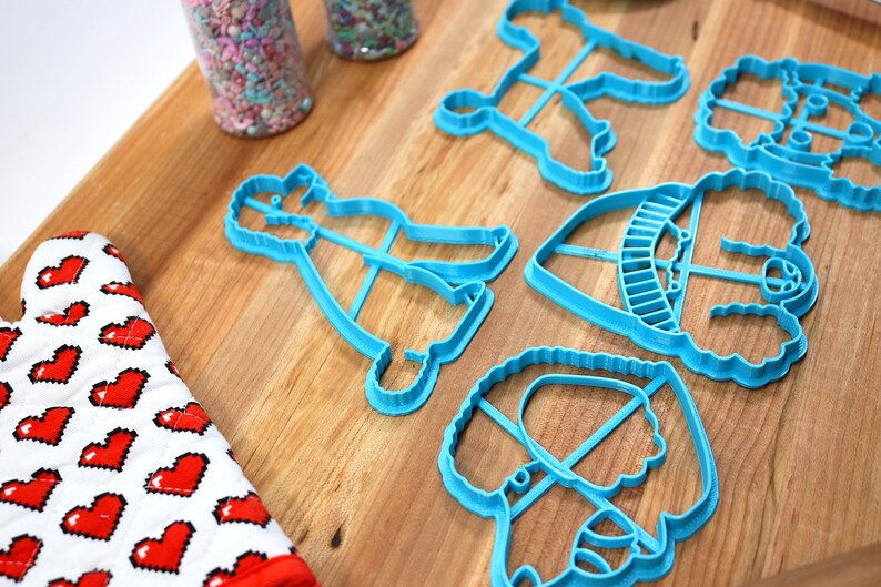 May include: A set of six blue plastic cookie cutters shaped like different dogs. The cutters are on a wooden surface.
