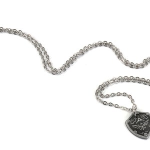 May include: A silver chain necklace with a pendant shaped like the Hylian Shield from the Legend of Zelda video game series.
