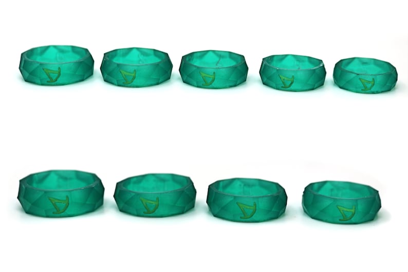 Pu&ograve; includere: Dieci anelli in silicone verde con un design geometrico e un piccolo logo al centro.