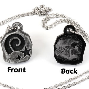 May include: A silver necklace with a pendant featuring a spiral and two stars on the front and a textured design on the back.