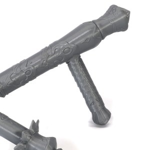 May include: A gray, intricately designed, metal weapon with a handle and a long, pointed blade. The weapon has a decorative pattern on the handle and blade.