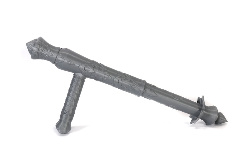 May include: A gray, intricately designed, 3D printed weapon with a long, cylindrical barrel and a shorter, perpendicular handle. The weapon has a pointed tip and a decorative design.