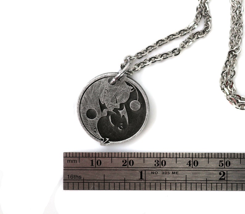 May include: A silver necklace with a round pendant featuring a yin yang symbol with a dragon and a phoenix design. The pendant is approximately 2 cm in diameter.